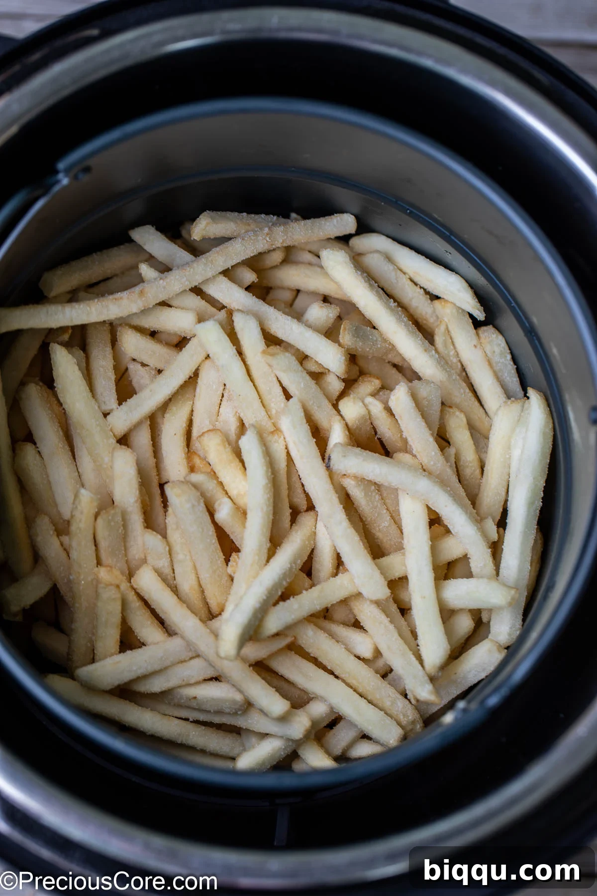 Frozen fries carefully placed in a round air fryer basket, ready for cooking.