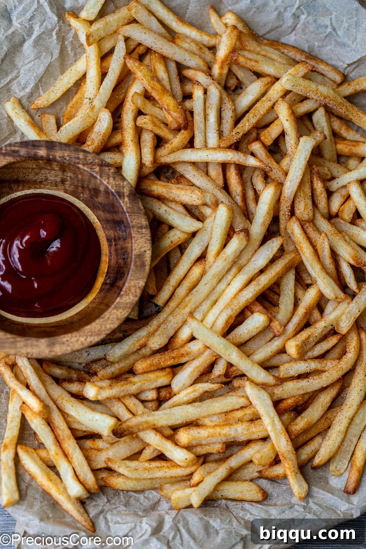 A close-up view of perfectly air-fried French fries, golden brown and crispy, with a small bowl of classic ketchup for dipping.