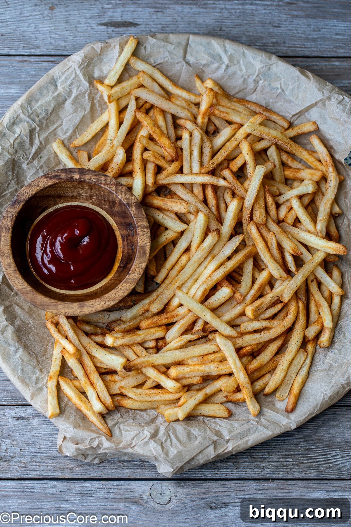 A perfectly arranged platter of crispy air-fried French fries, accompanied by a small bowl of ketchup for dipping.