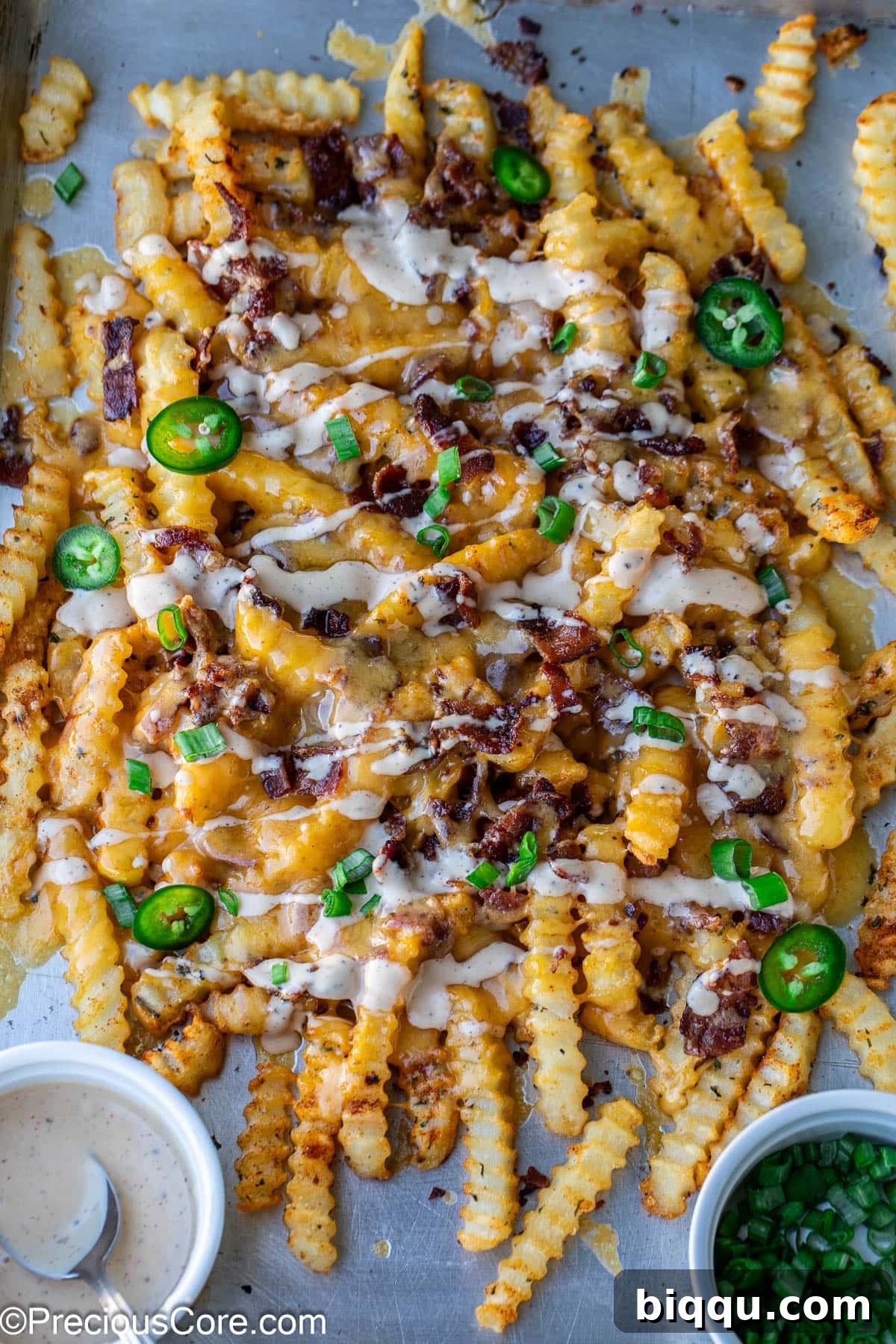 Loaded French Fries on a sheet pan, ready to be served, highlighting their crispy texture and abundant toppings.