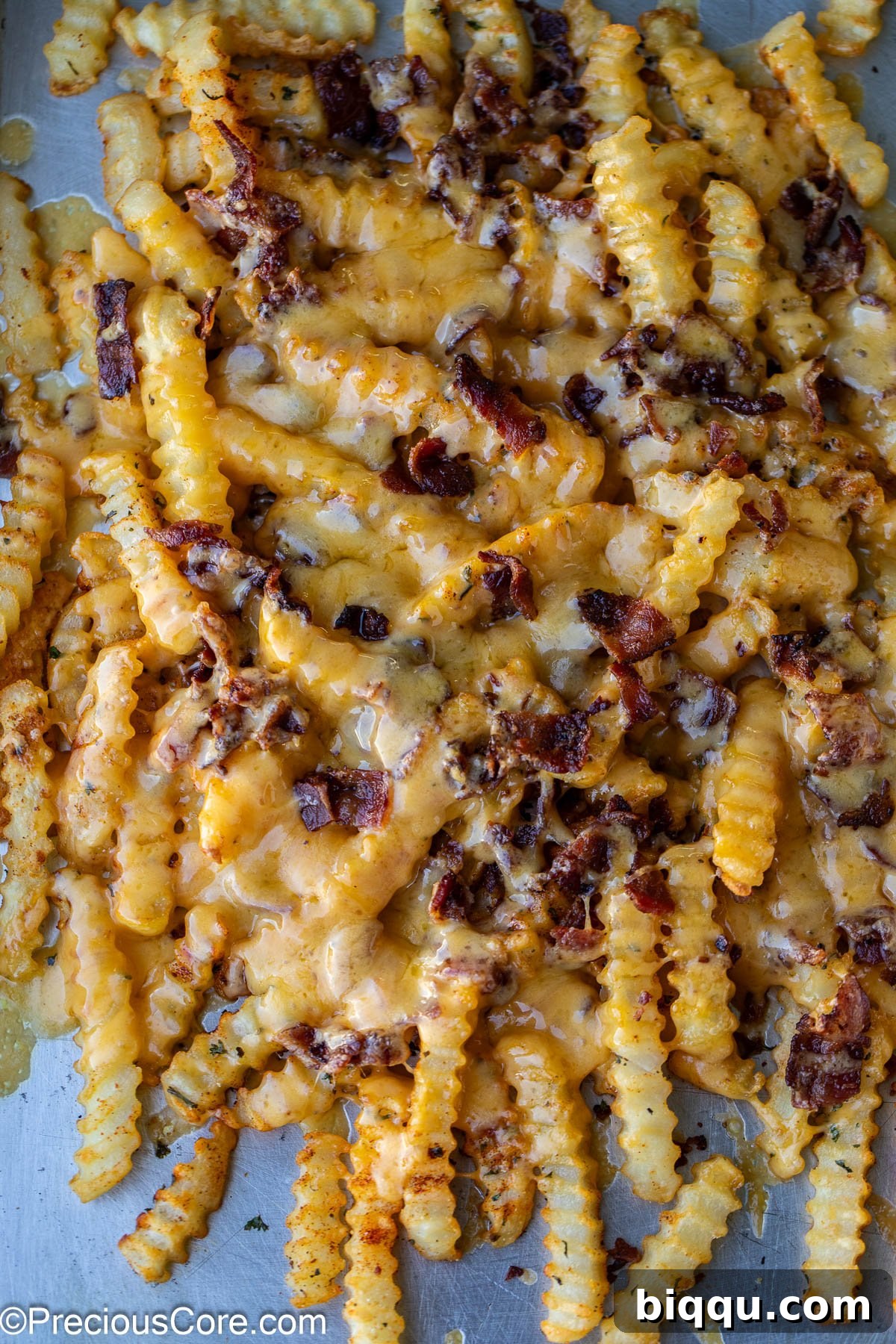 Loaded French Fries fresh from the oven, with perfectly melted, gooey cheddar cheese and crispy bacon. The cheese is golden and bubbling.