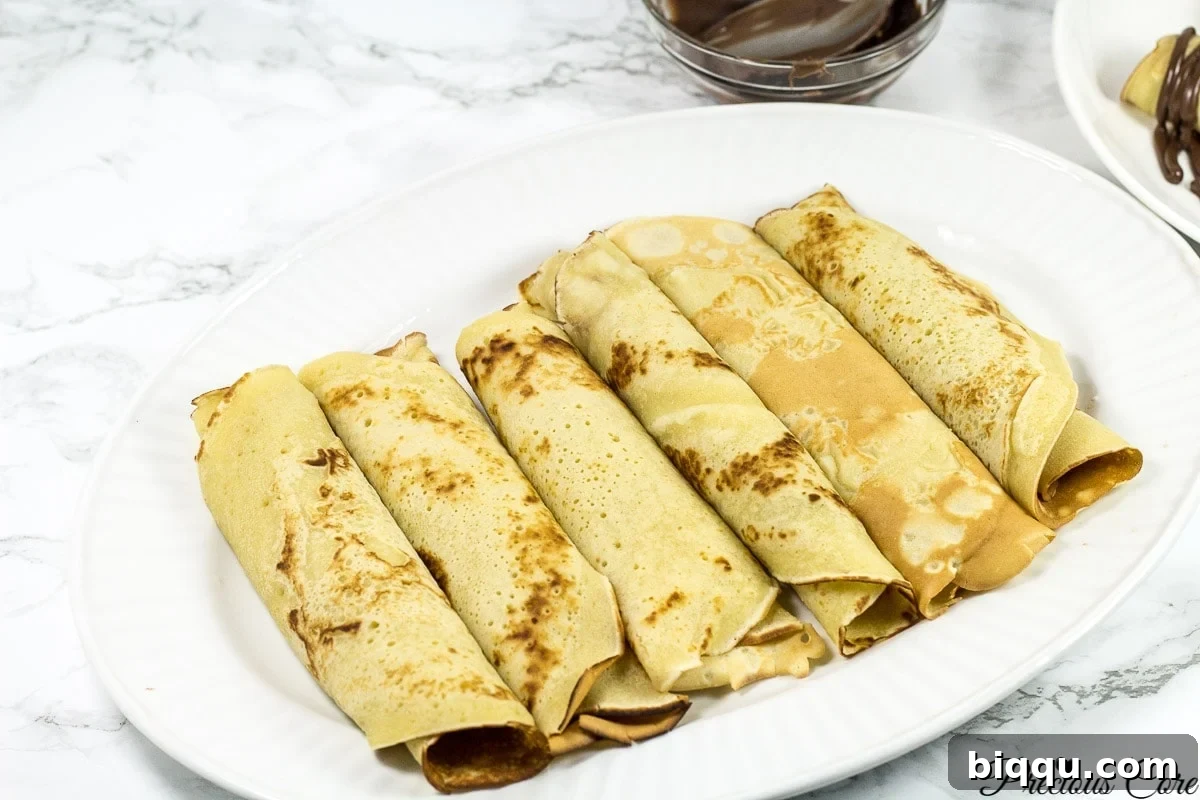 Cameroonian pancakes rolled on a white plate.