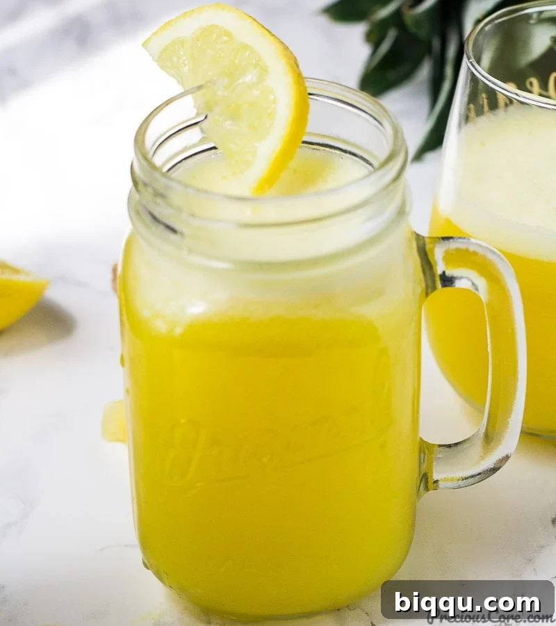 A mason jar of pineapple ginger juice decorated with a half moon lemon slice.
