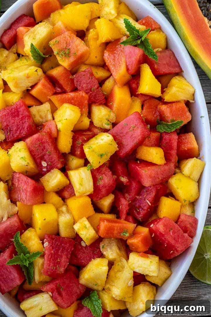 Tropical fruit salad in a white oval serving bowl.