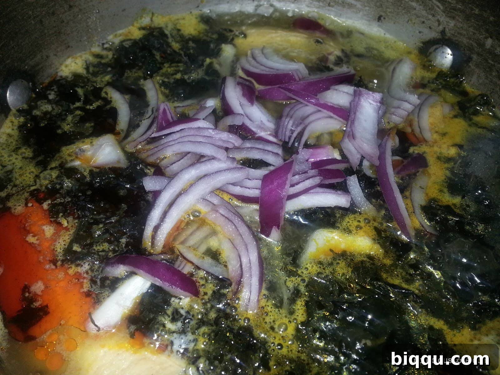 Finely chopped onions are added to the simmering Born House Planti ingredients, contributing to the dish's aromatic base.