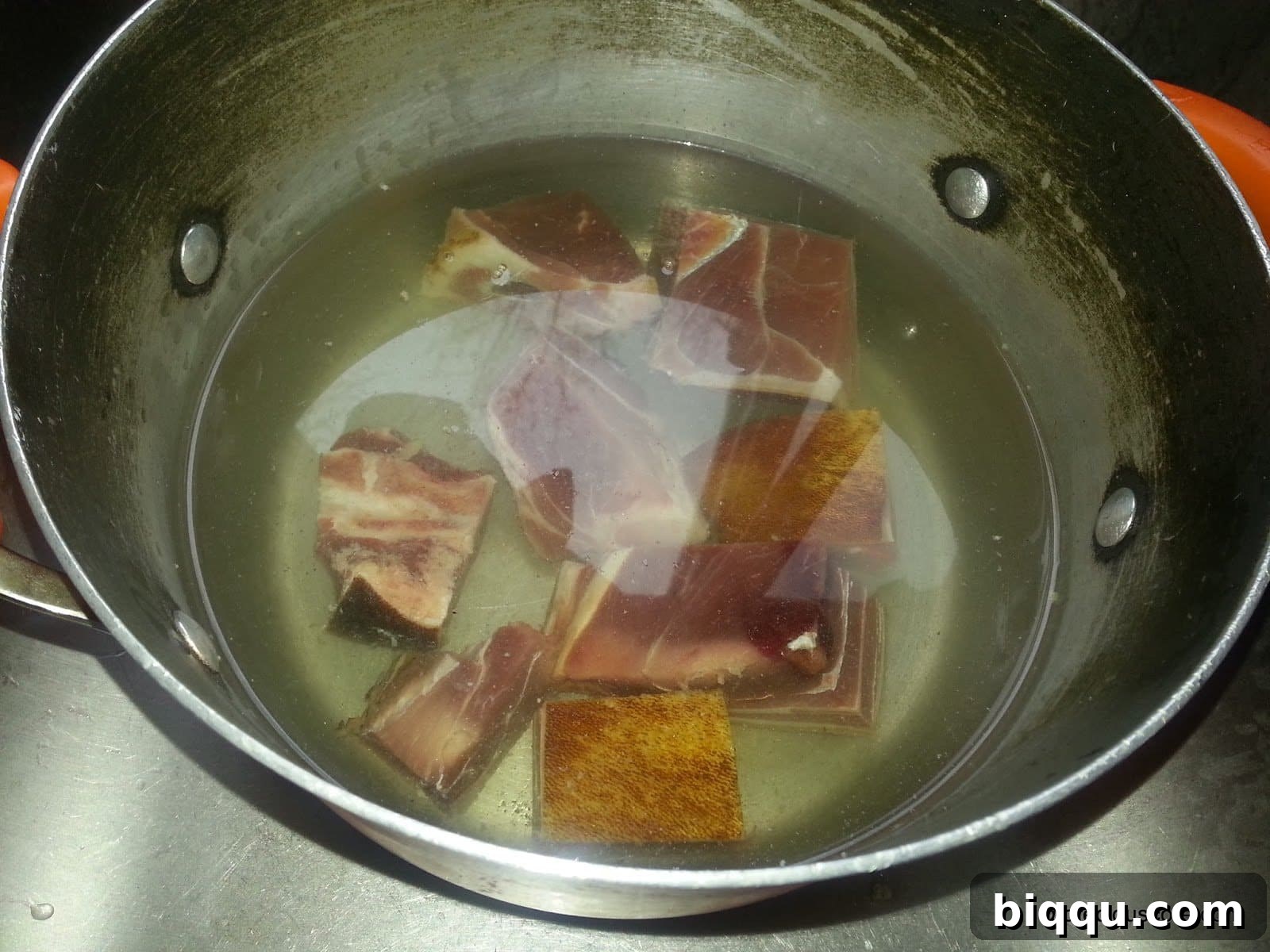 Smoked goat meat boiling in a pot, creating a flavorful base for the Born House Planti recipe.