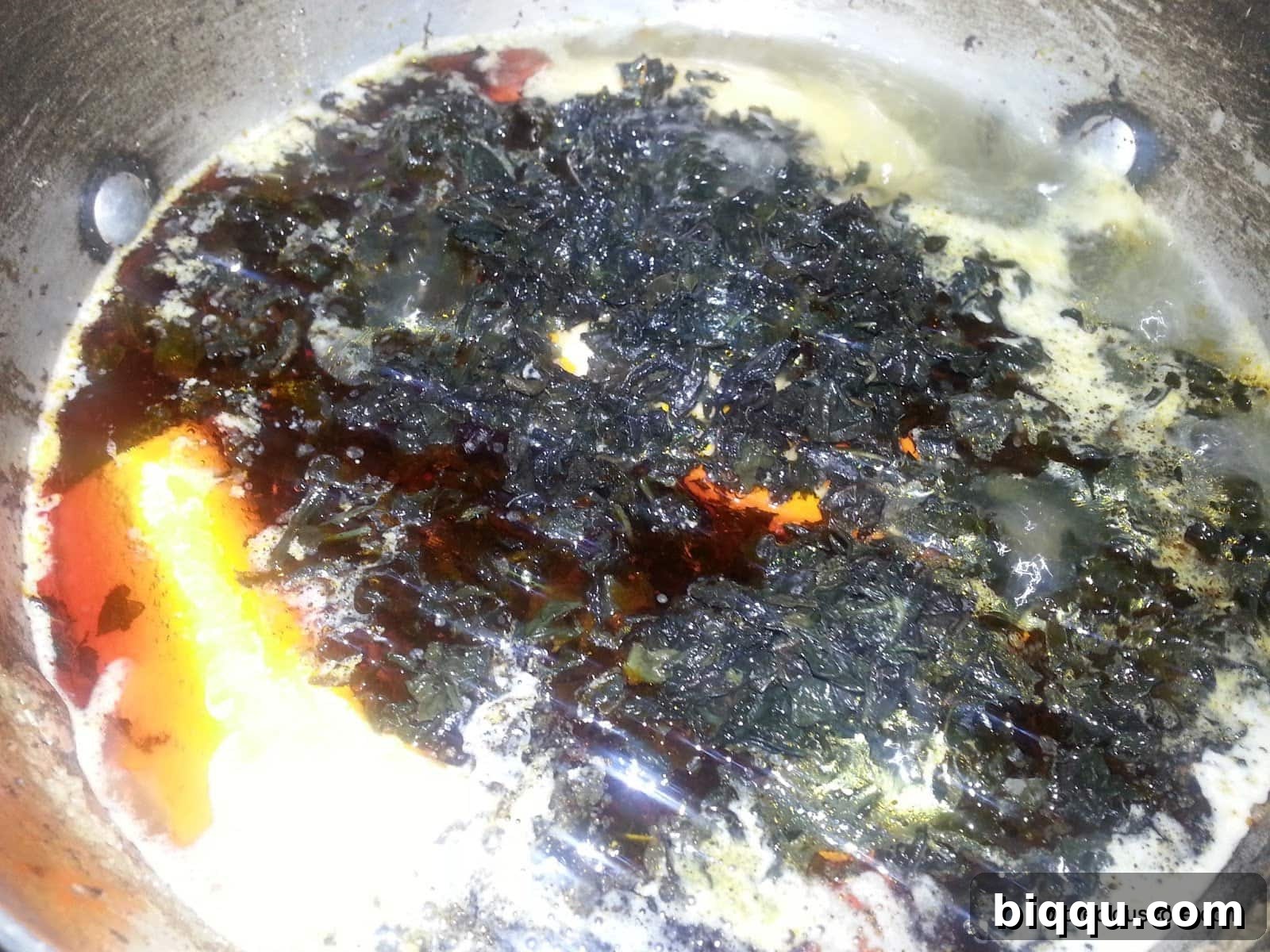 Washed bitterleaves being added to the pot of plantains, meat, and palm oil, blending the key flavors of Born House Planti.