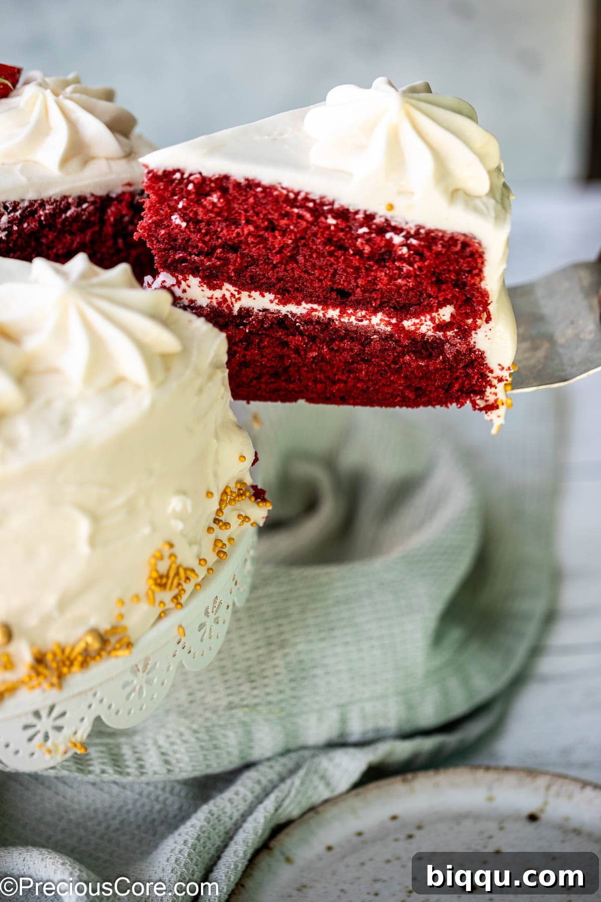 Velvet Dream Cake Without Buttermilk 16 A slice of red velvet cake being lifted with a cake server, highlighting its rich layers and creamy frosting.