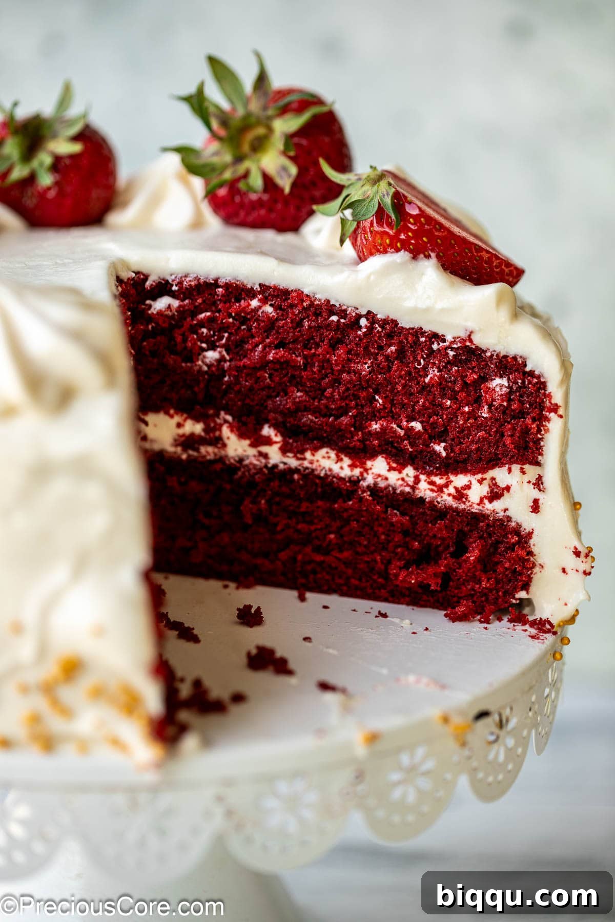 Velvet Dream Cake Without Buttermilk 4 Close-up view of a red velvet cake, sliced to reveal its moist, soft crumb and even red color, topped with creamy white frosting.