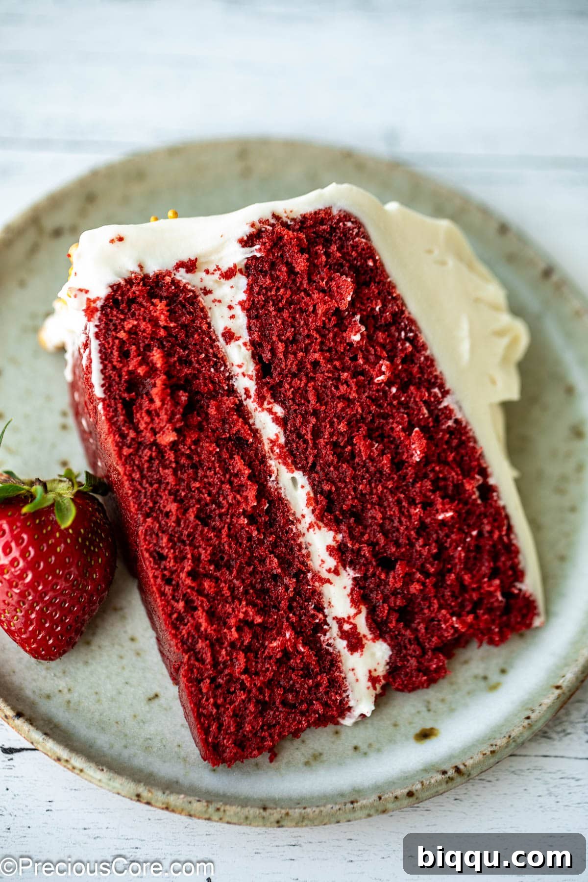 Velvet Dream Cake Without Buttermilk 7 A perfectly portioned slice of red velvet cake without buttermilk, garnished with a fresh strawberry, on a white plate.