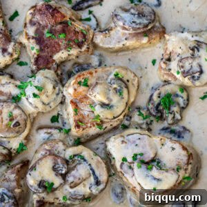 Cooked pork tenderloin in a creamy sauce with mushrooms, ready to be served.