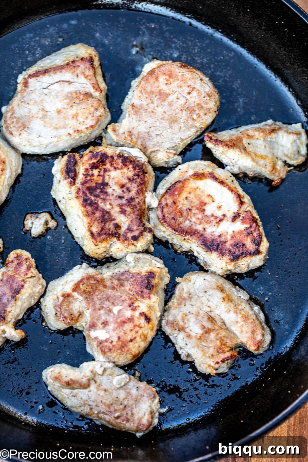 Golden-brown seared pork medallions cooking in a hot cast iron skillet, creating a flavorful crust.