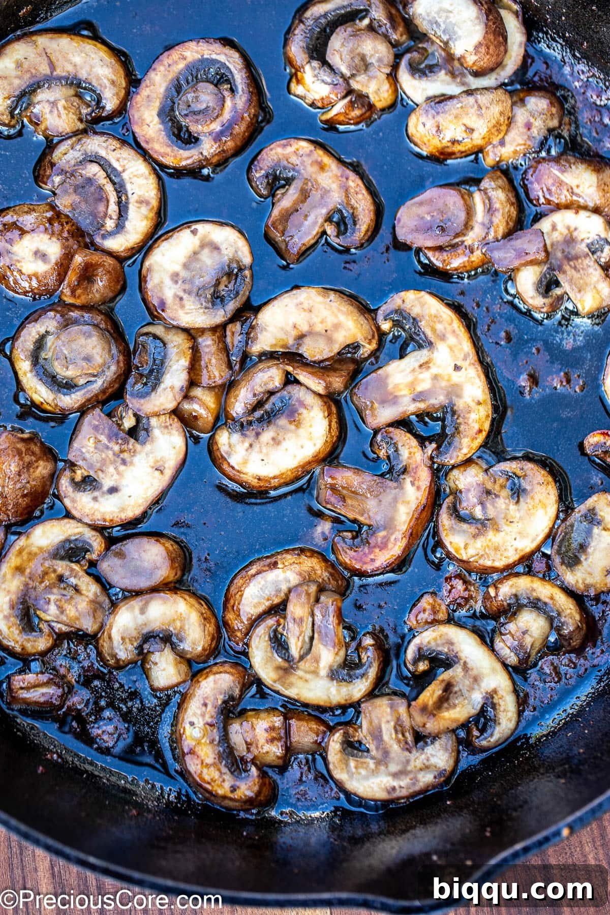 Sliced mushrooms being sautéed in butter in a skillet, turning golden and tender.