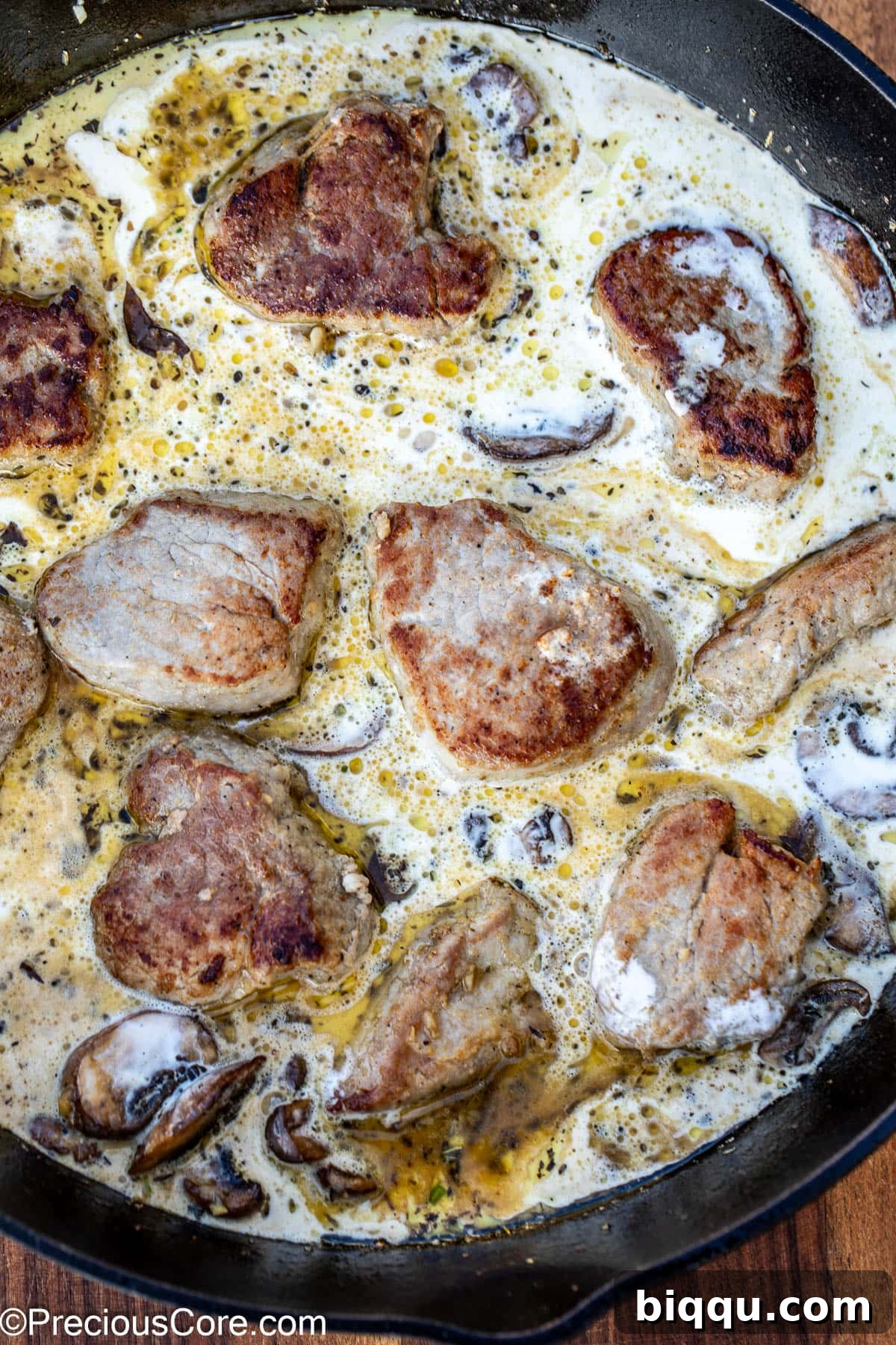 Pork medallions simmering in a skillet, generously coated in a rich, creamy mushroom sauce.