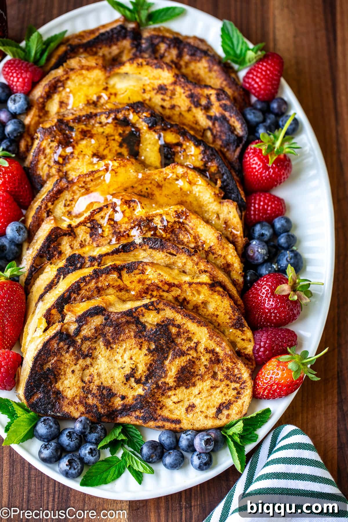 Golden-brown slices of Sourdough French Toast beautifully arranged on a white oval plate, ready to be served.