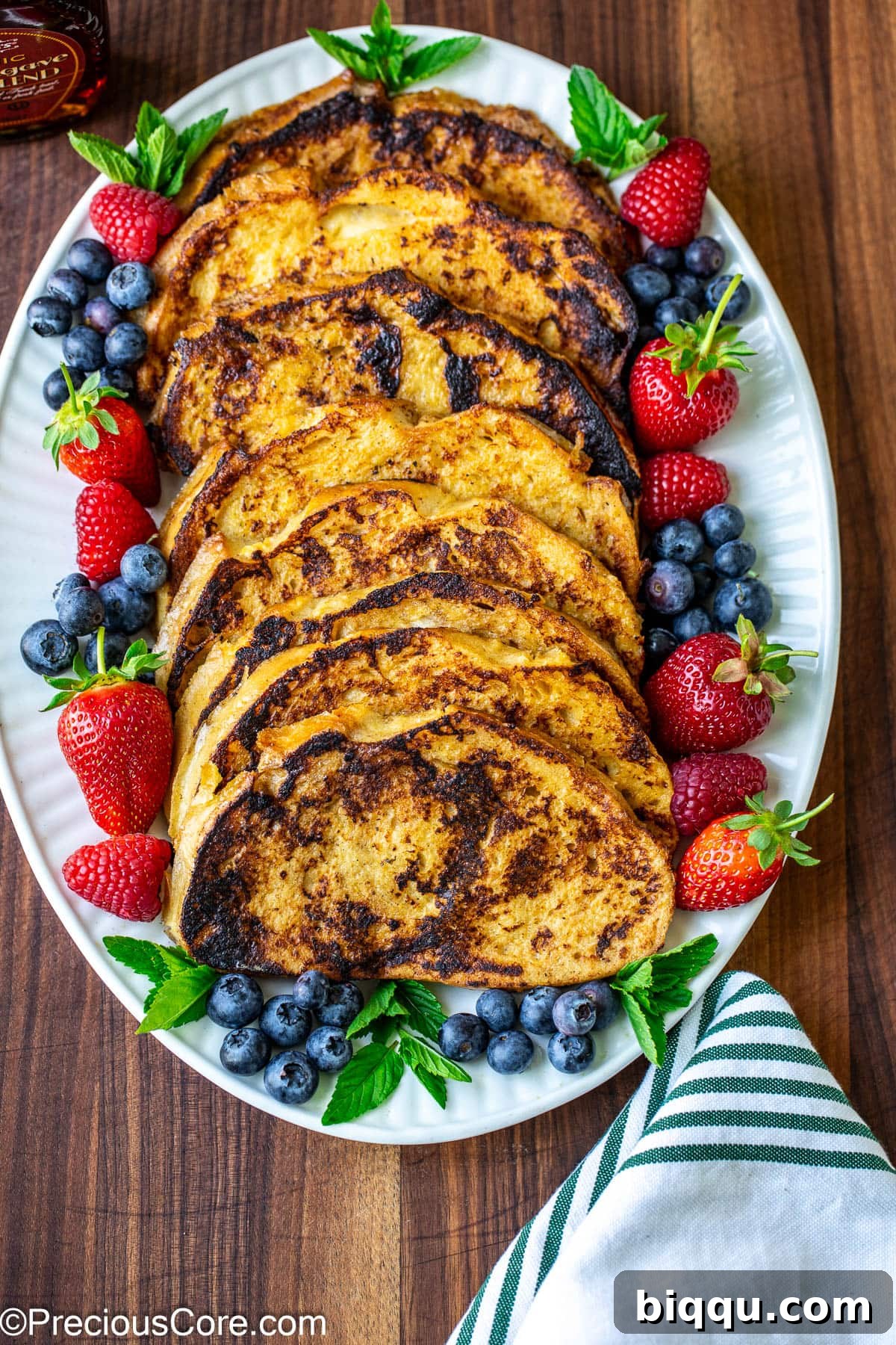 Freshly cooked French toast slices neatly stacked on a elegant serving plate, ready for toppings.