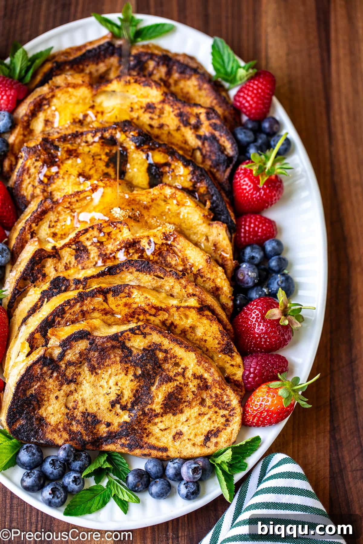Plated Sourdough French Toast adorned with fresh mixed berries and a generous pour of maple syrup.