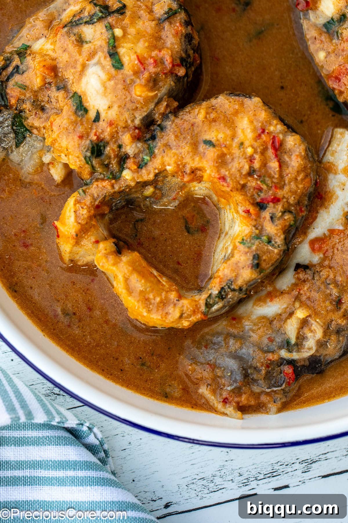 A close-up view of tender fish steaks nestled in a fragrant, spicy broth, highlighting the vibrant colors and textures of the soup.
