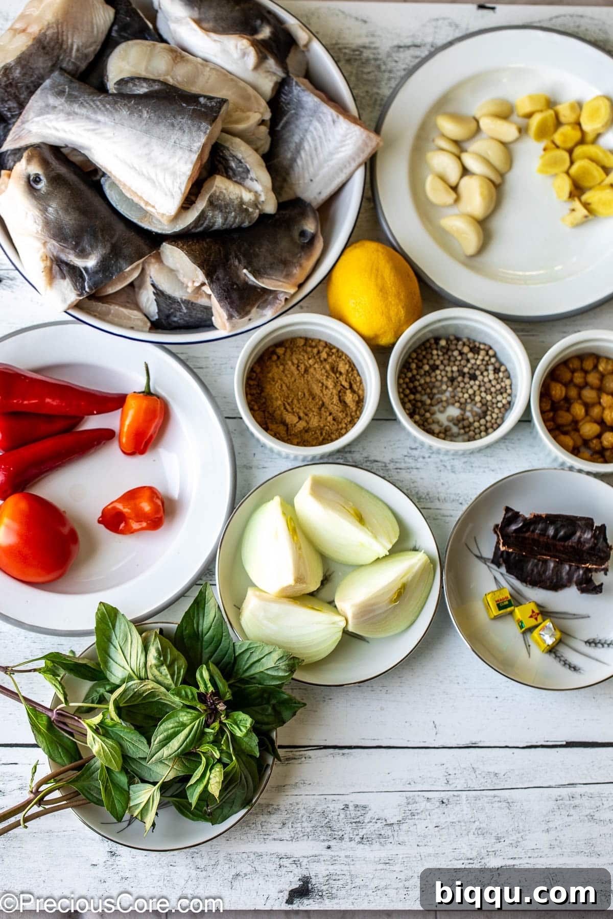 A beautiful flat lay photograph showcasing all the fresh ingredients needed for Catfish Pepper Soup, neatly arranged on a white surface.