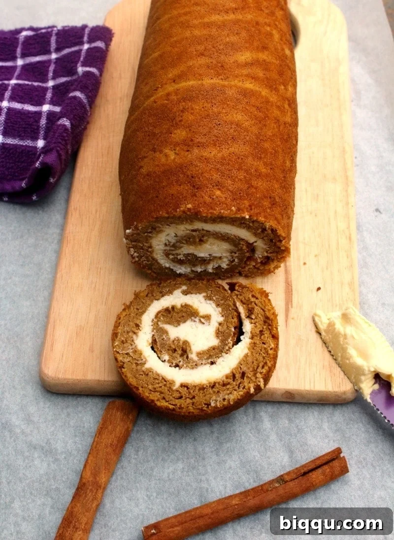 A freshly baked Pumpkin Roll Cake cooling on a chopping board.