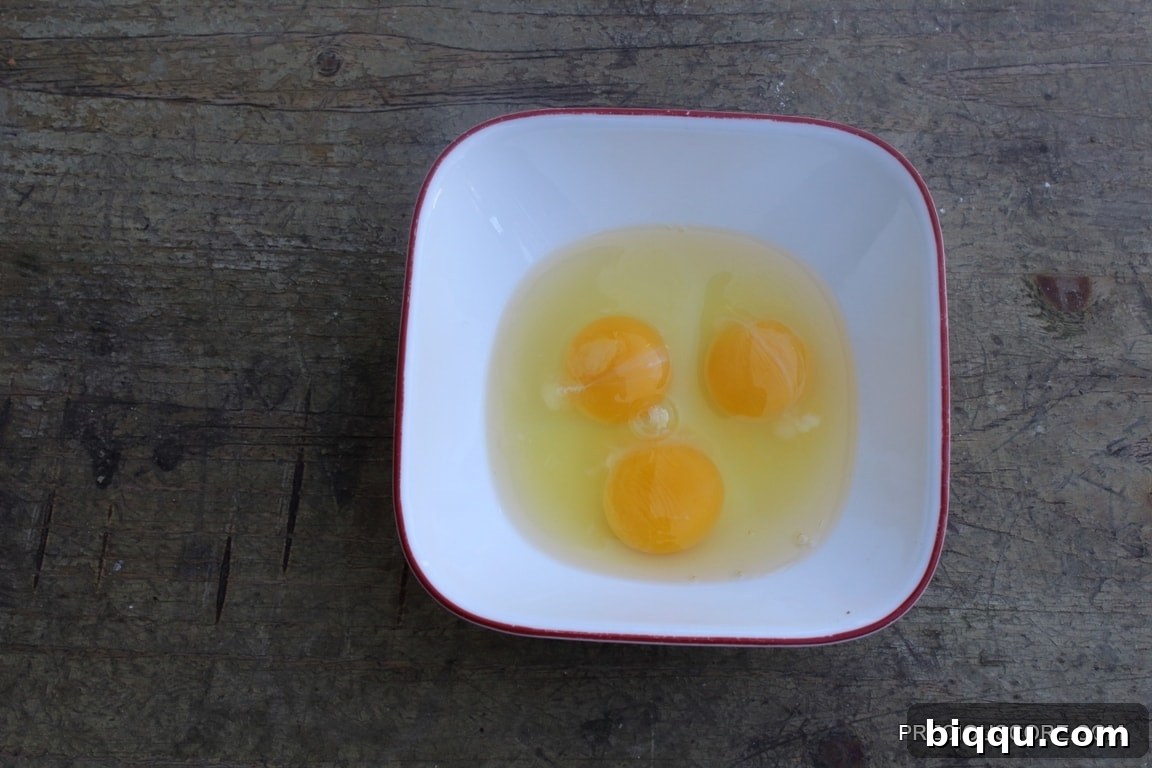 Three eggs in a bowl, waiting to be used in the cake batter.