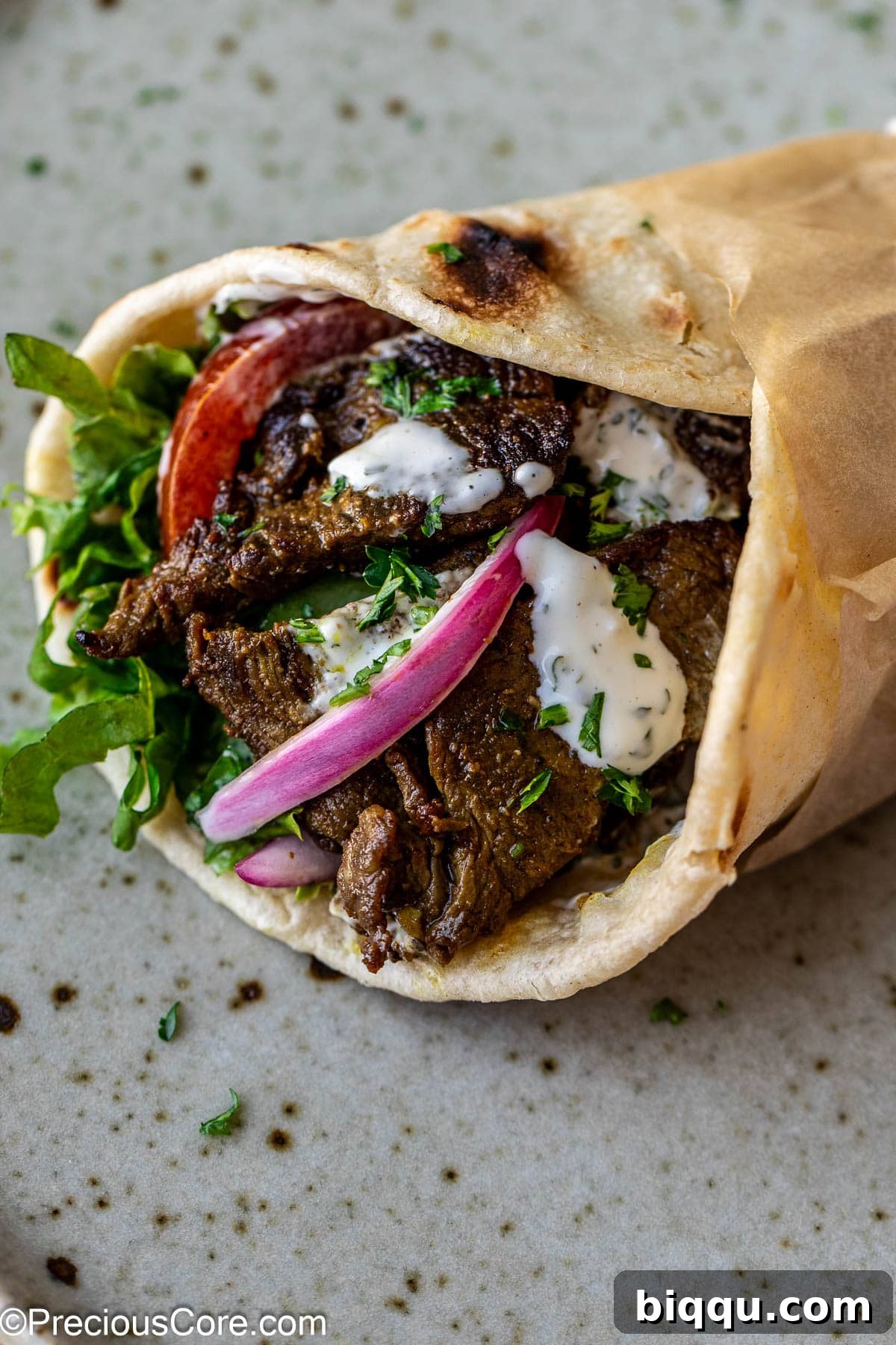 Beef shawarma wrap with veggies and sauce.