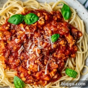 Spaghetti in a bowl topped with chicken Bolognese sauce.