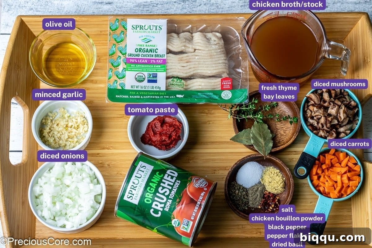 A selection of fresh and canned ingredients for Spaghetti Bolognese Chicken, including ground chicken, crushed tomatoes, onions, garlic, and various herbs and spices, neatly arranged on a tray.