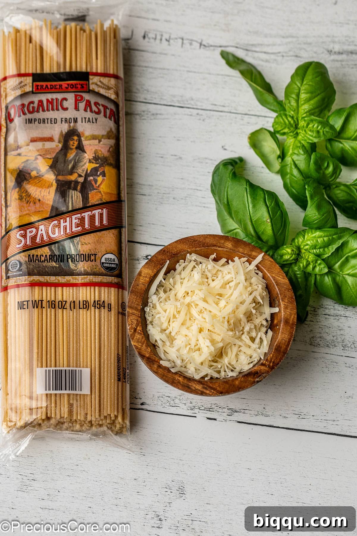 A vibrant display of cooked spaghetti, a bowl of shredded Parmesan cheese, and fresh basil leaves, all ready to accompany the Chicken Bolognese sauce.