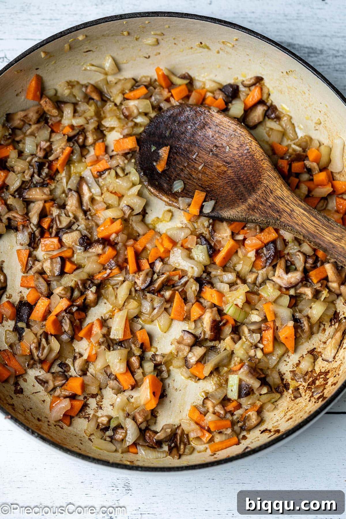 Finely diced onions, carrots, and mushrooms are sautéing in olive oil in a large pot, creating the aromatic base for the Bolognese sauce.