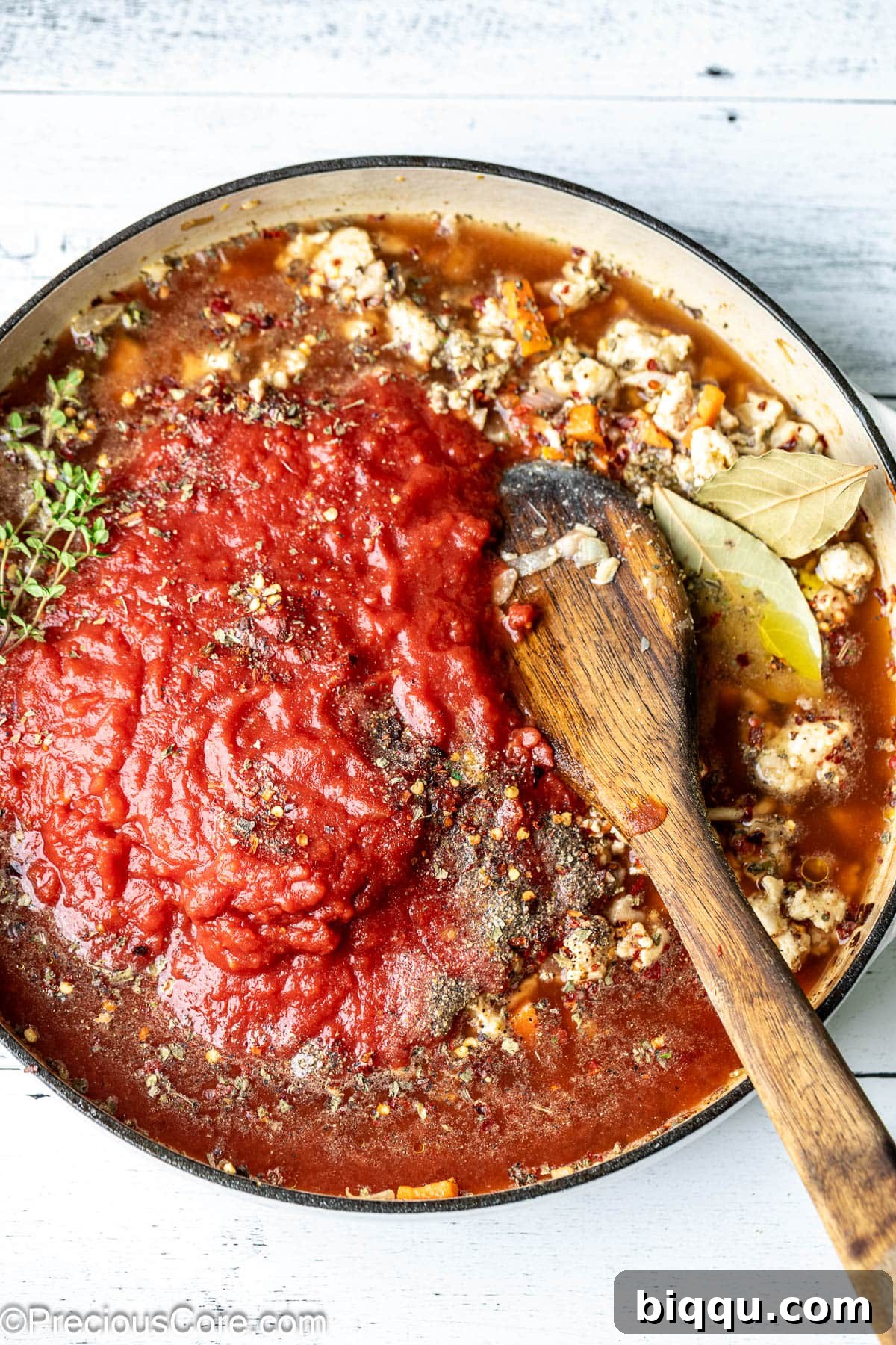All the ingredients for the Chicken Spaghetti Bolognese sauce, including chicken stock, tomato paste, crushed tomatoes, herbs, and seasonings, have been added to the pot and are ready to simmer.