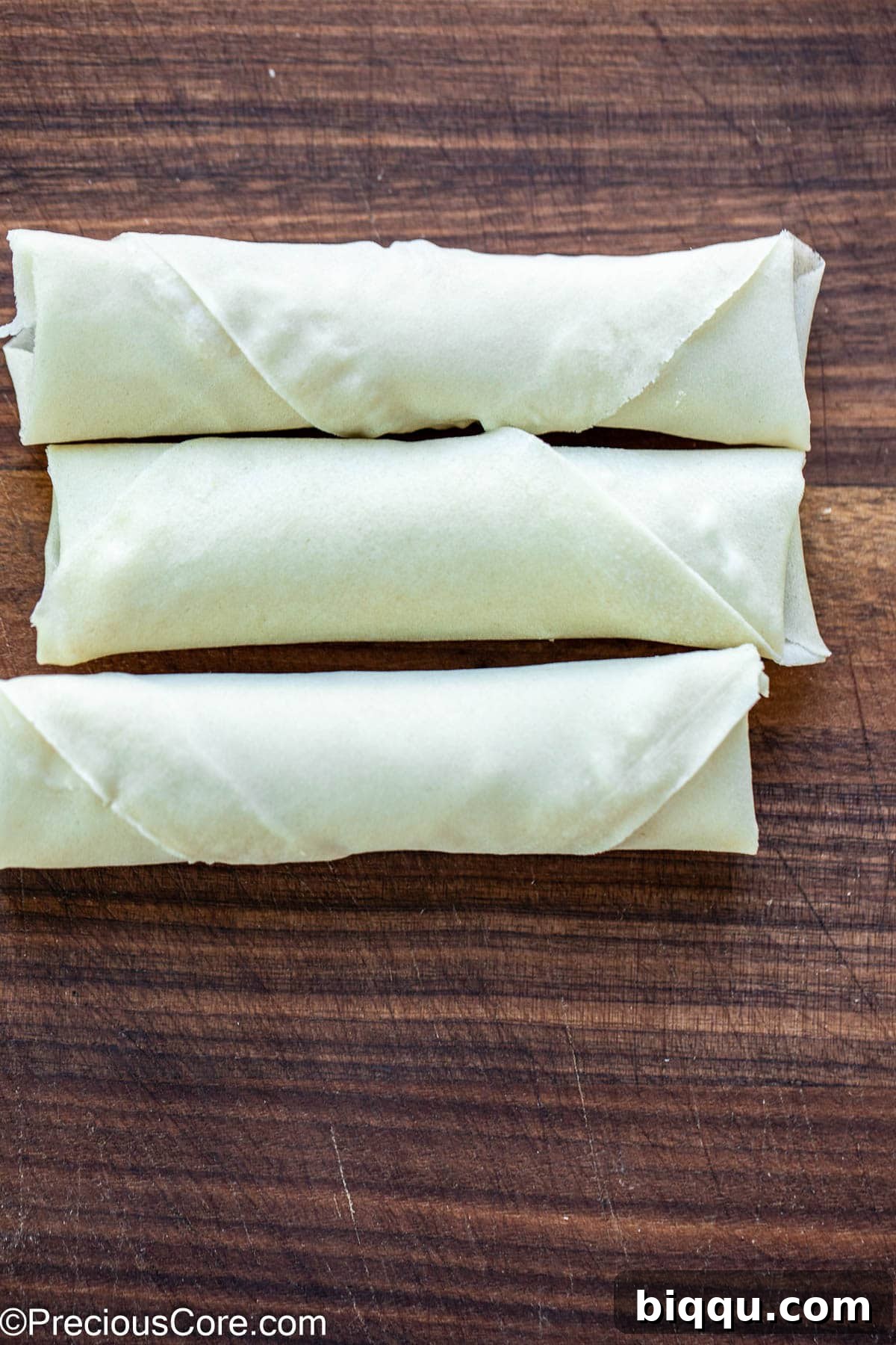 Savory Beef Spring Rolls 11 Neatly arranged ready-to-cook spring rolls on a tray.