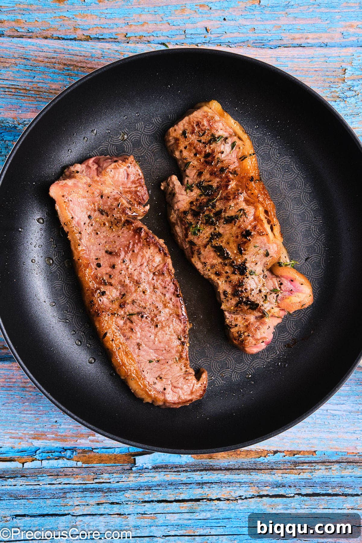Two perfectly seared steaks, showing a beautiful golden-brown crust, in a cast iron skillet.