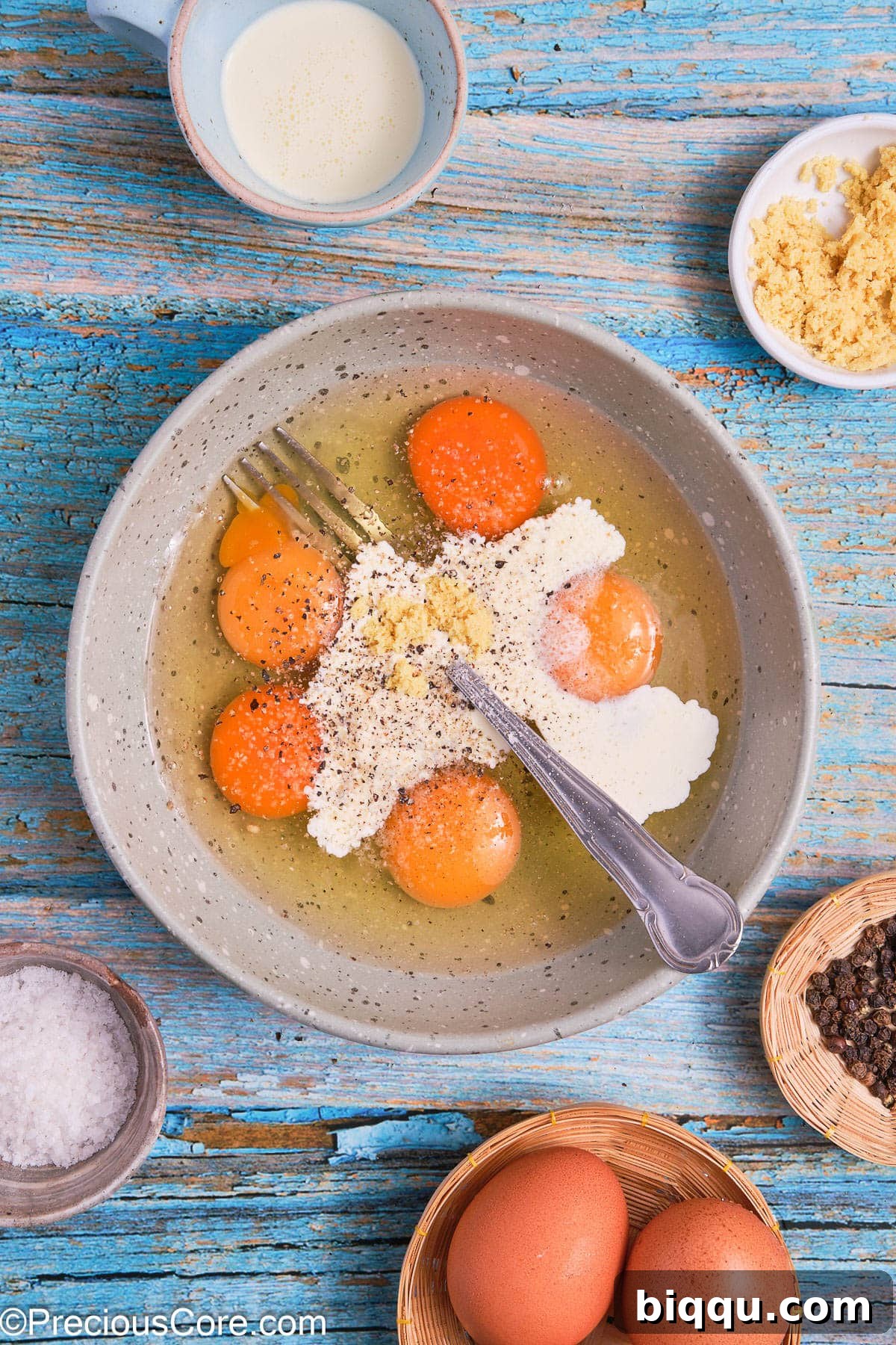 A bowl filled with cracked eggs, heavy cream, and seasonings, ready to be whisked.