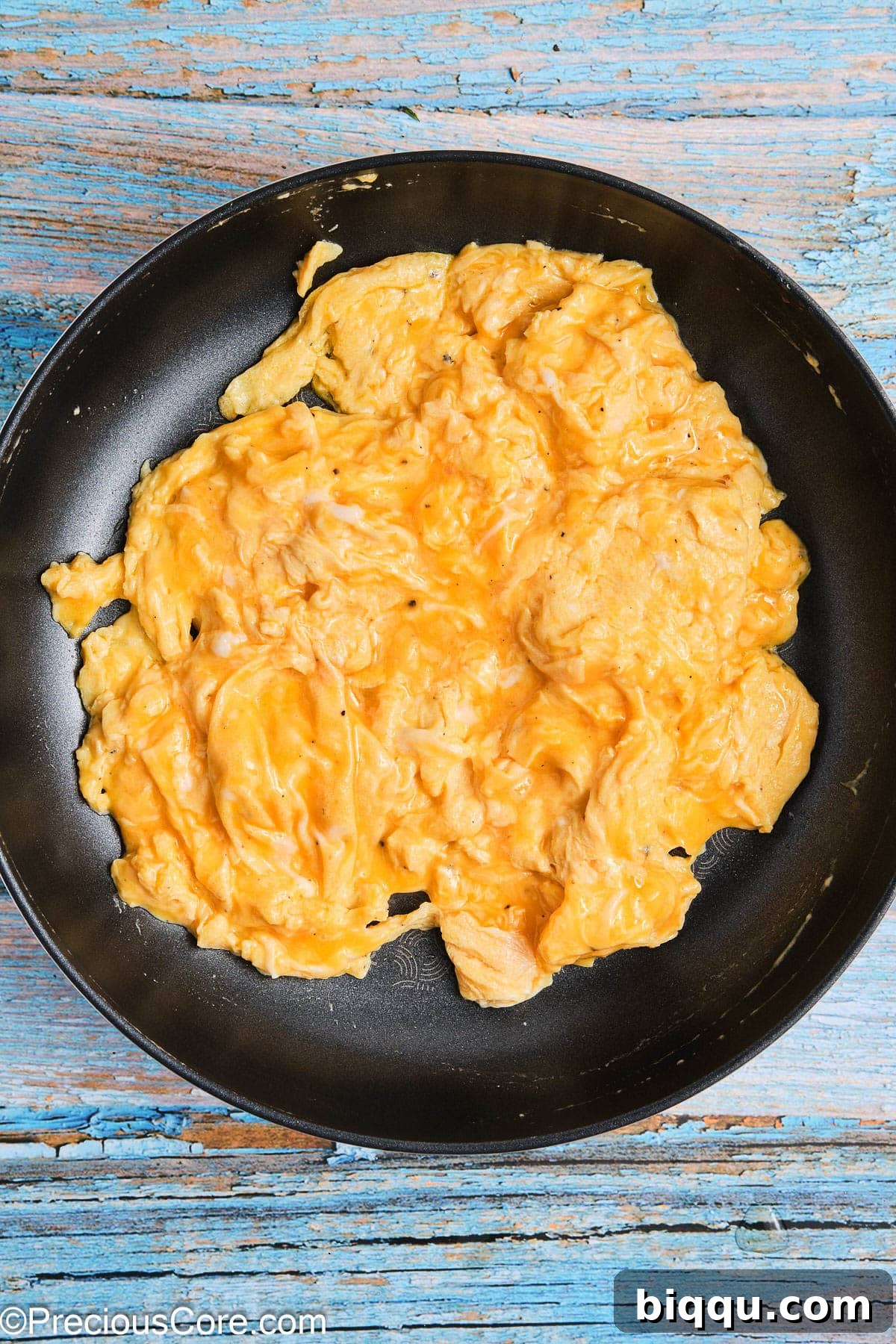 Soft, fluffy scrambled eggs cooking gently in a non-stick skillet, forming tender curds.