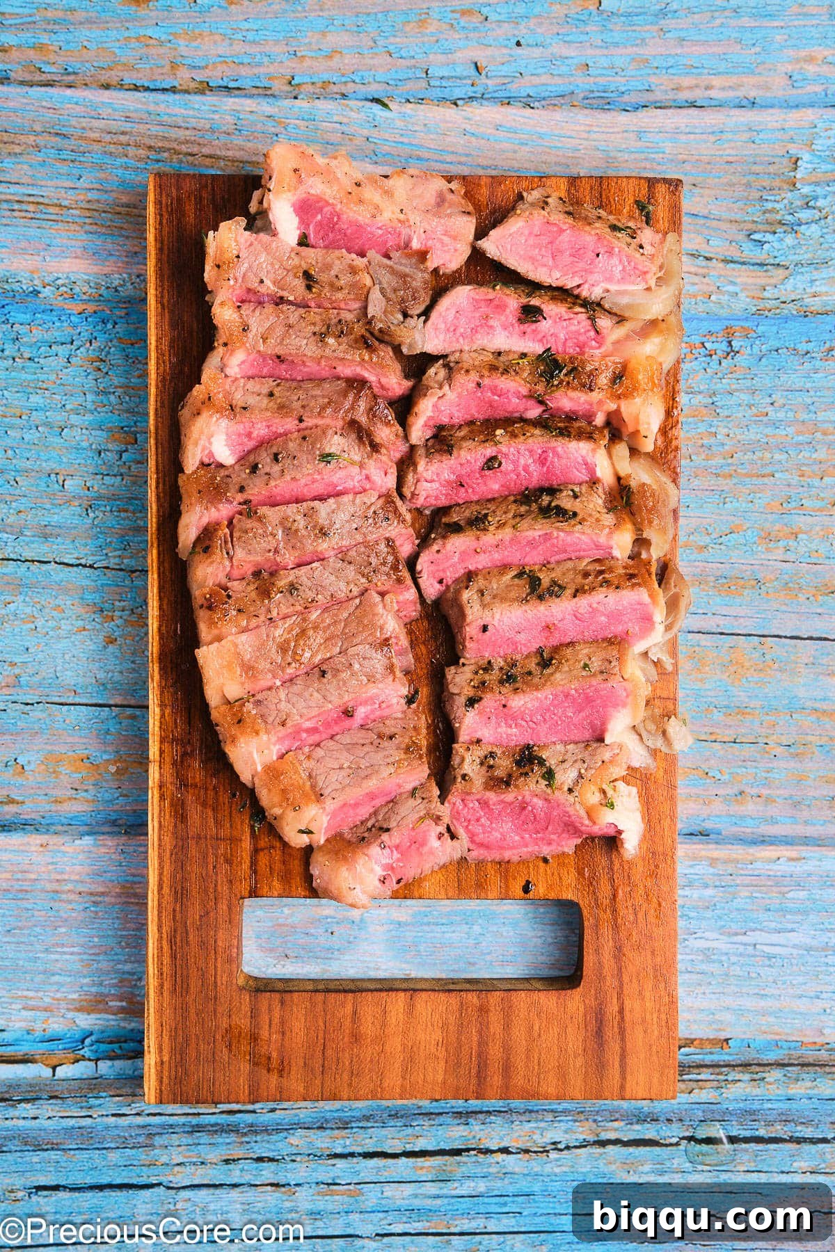 A perfectly cooked ribeye steak, expertly sliced against the grain on a wooden cutting board.