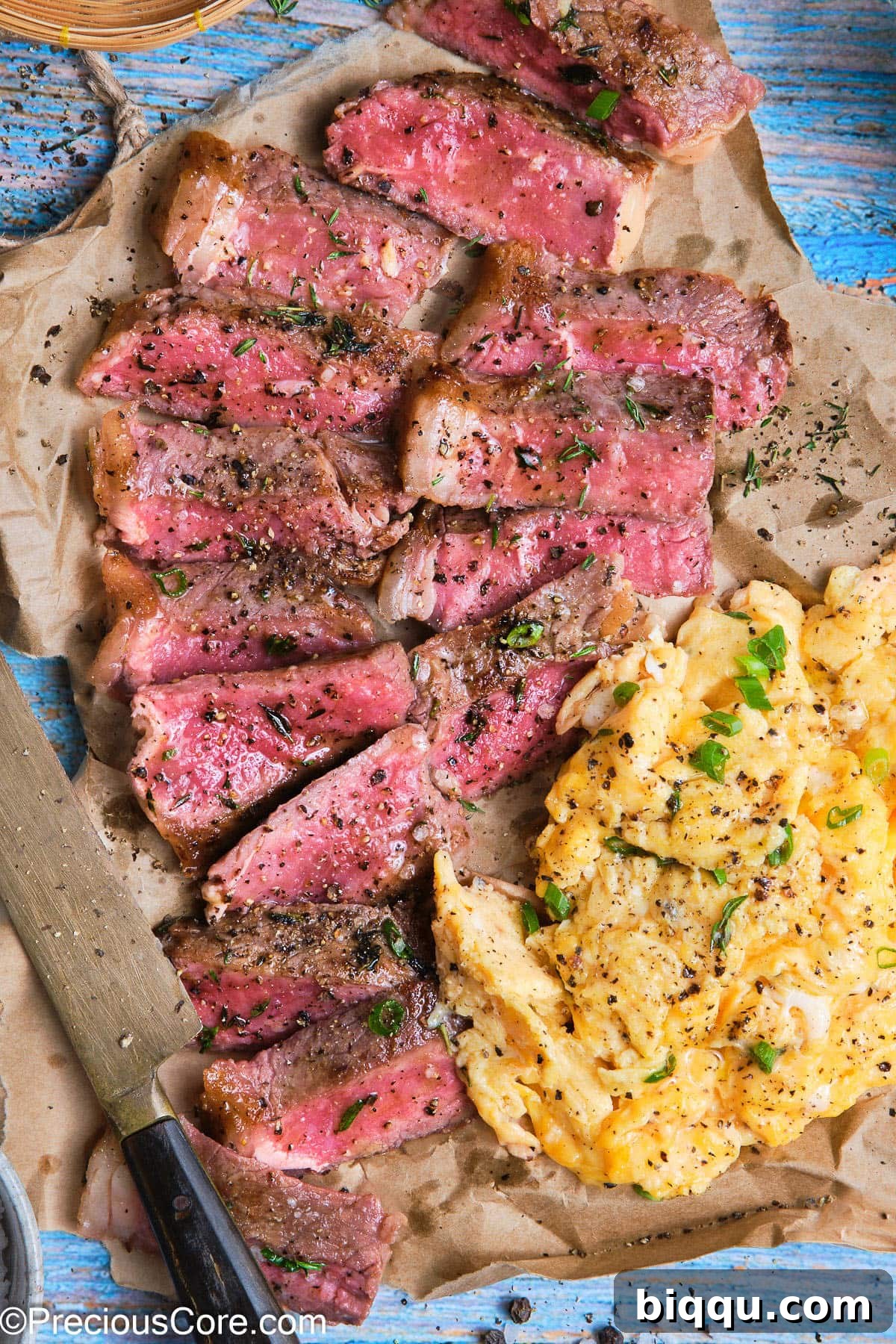 A perfectly cooked slice of juicy steak nestled next to a mound of soft, golden scrambled eggs, ready to be enjoyed.