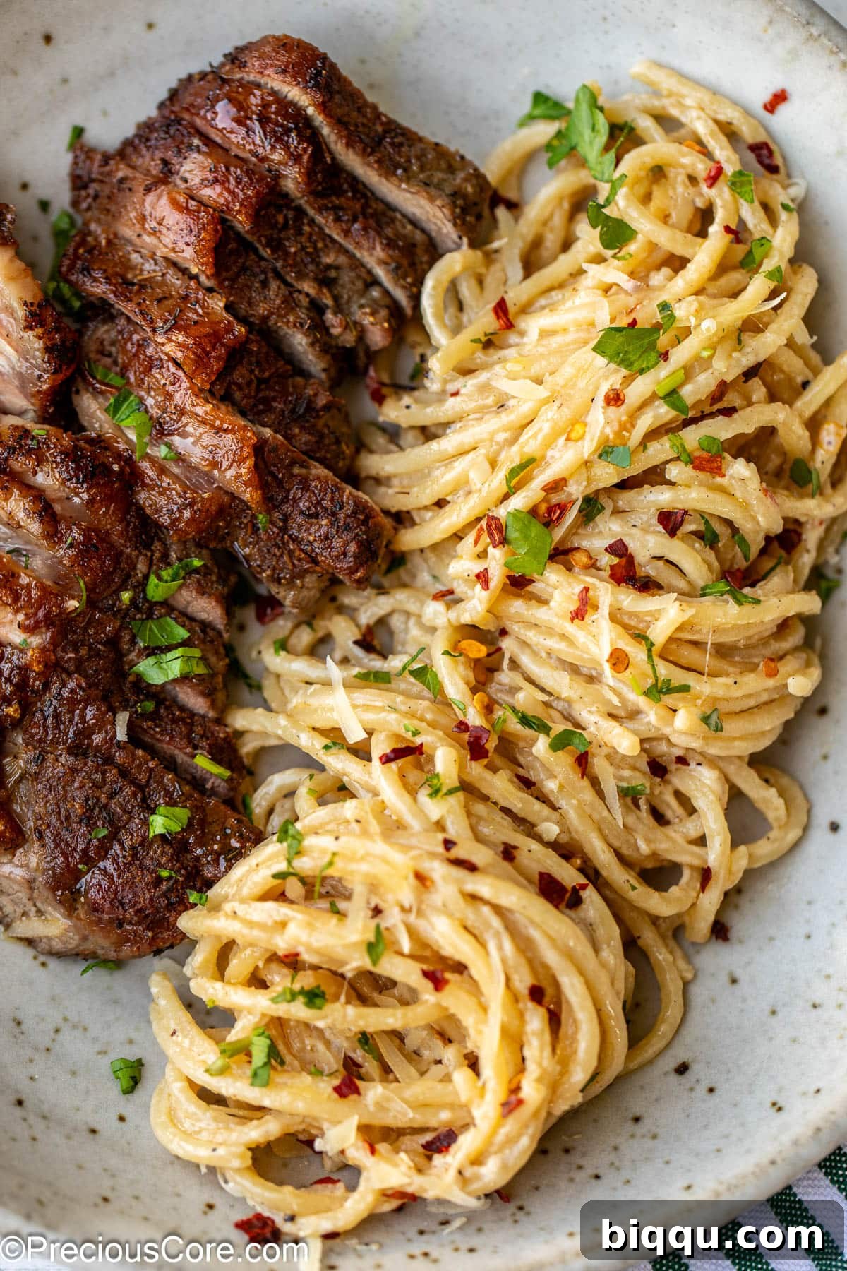 Sliced steak with cooked spaghetti in a bowl, ready to be tossed.