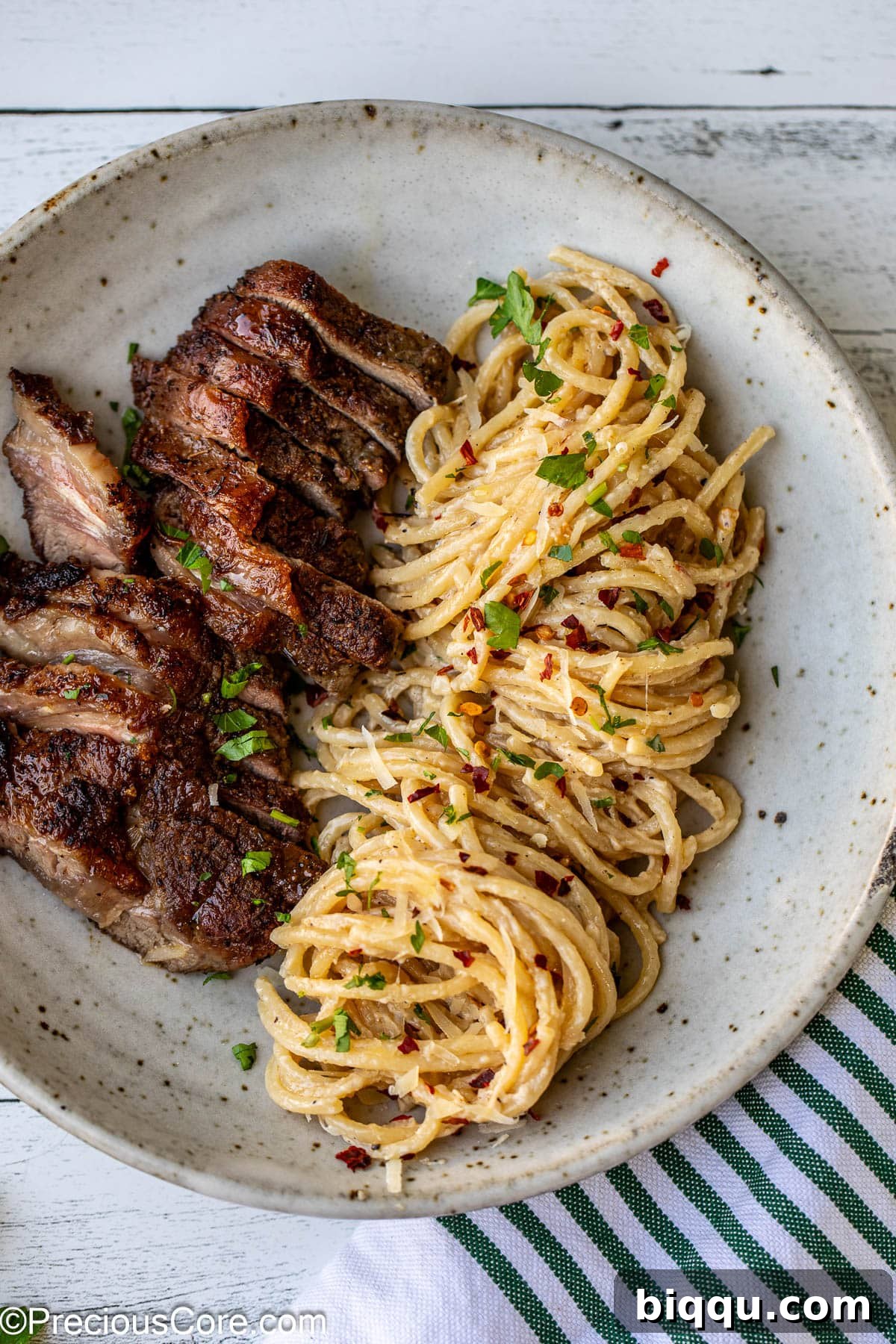 Plated steak and pasta garnished with fresh herbs, showcasing its elegance.