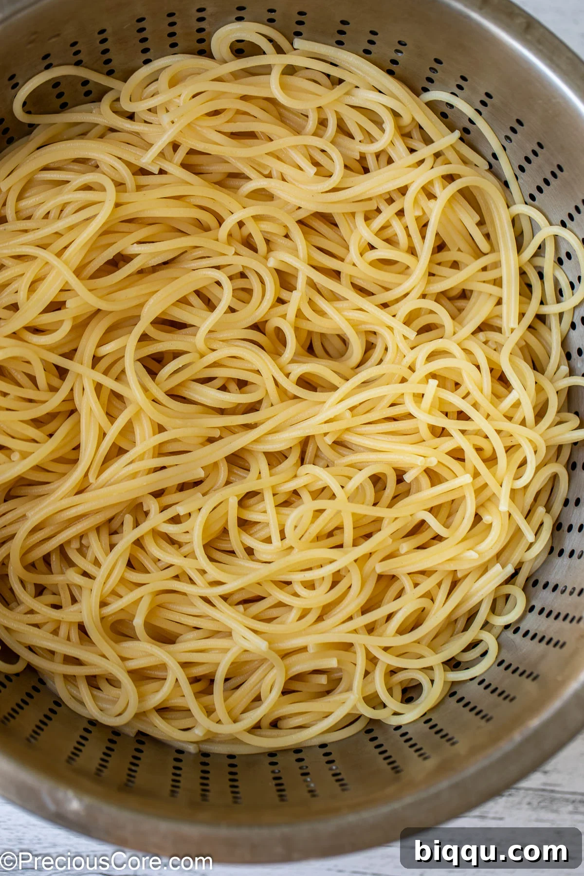 Cooked and drained spaghetti pasta in a strainer.