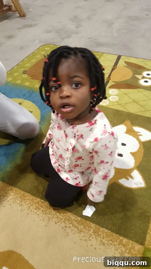 A toddler with newly braided hair, looking playful.