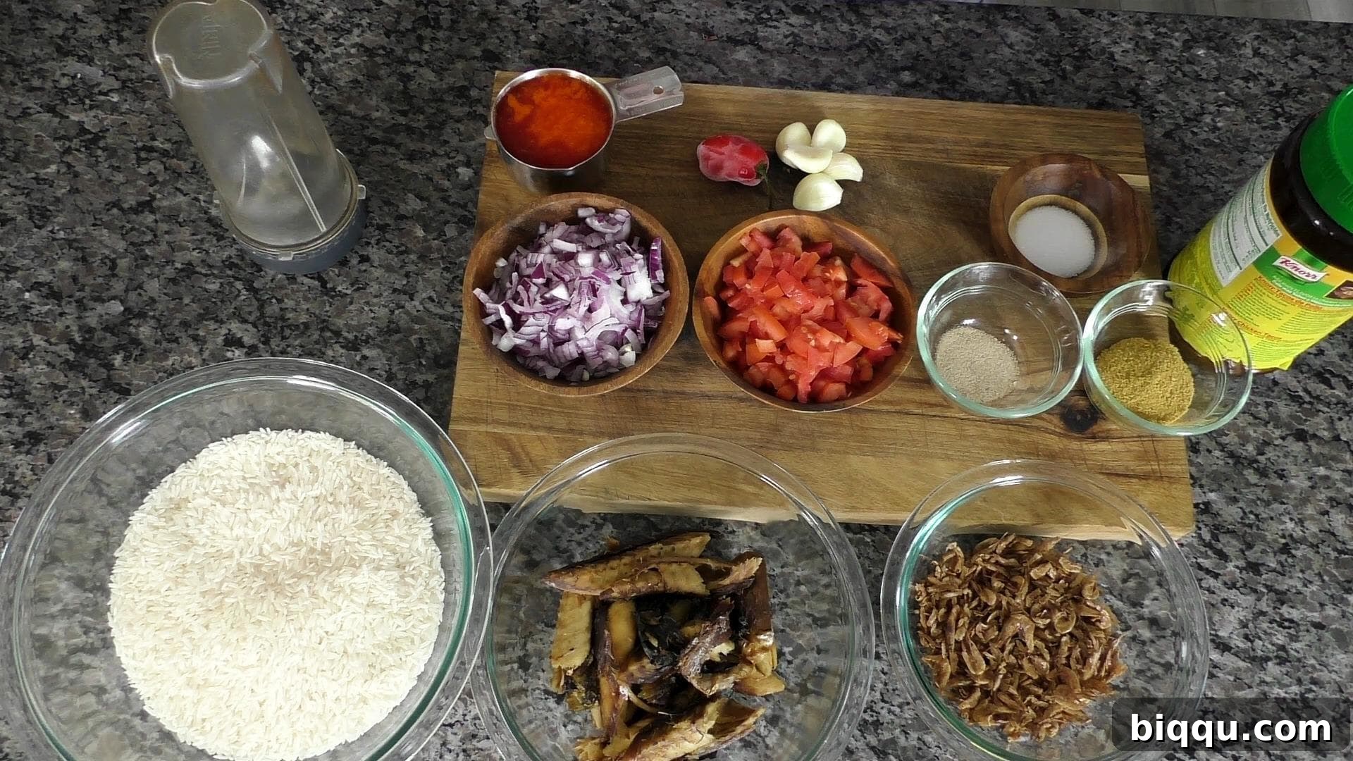 A vibrant display of fresh ingredients for Njanga Rice, including red palm oil, tomatoes, onions, crayfish, and rice.