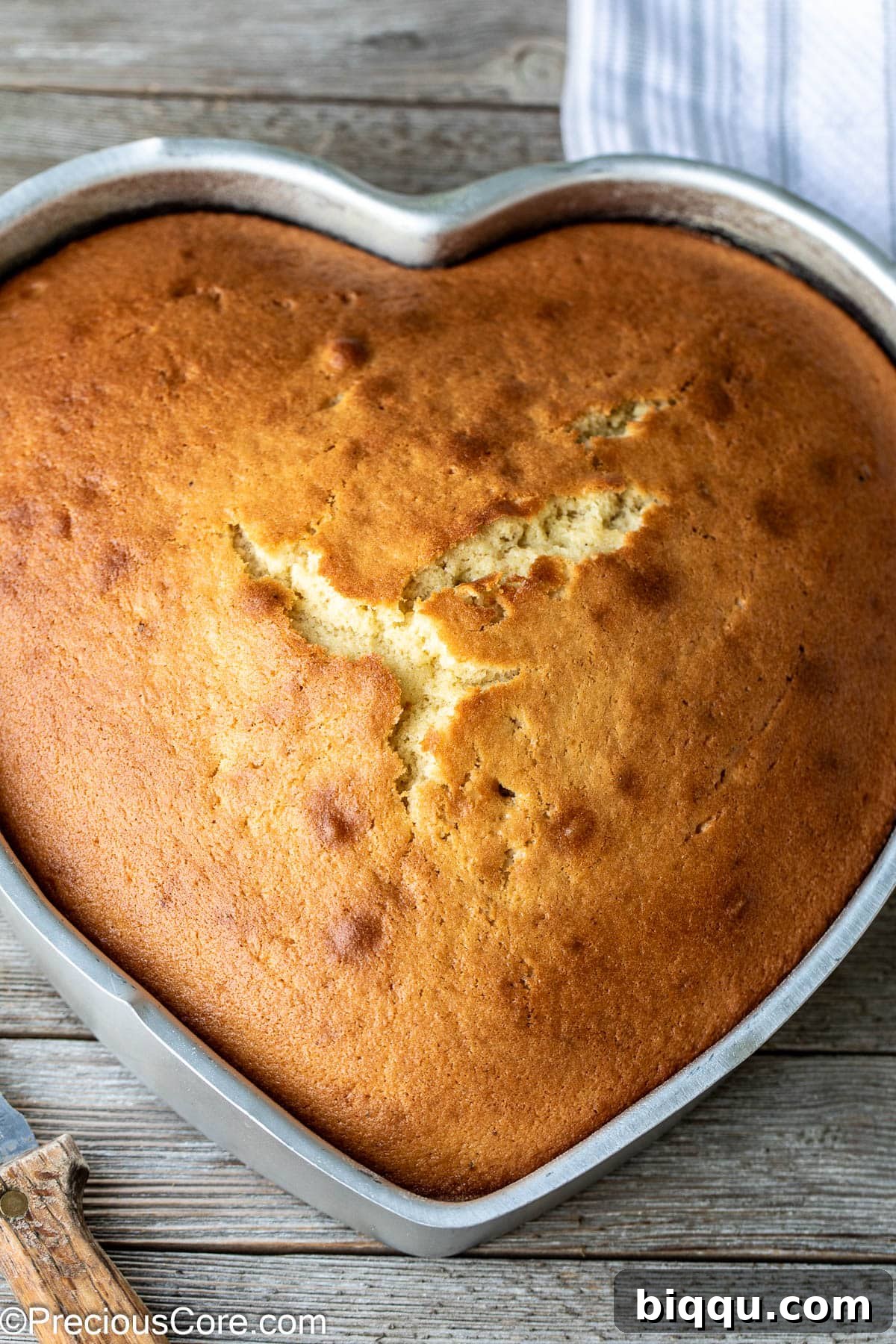 A heart-shaped plain cake still in its pan, freshly baked and golden.