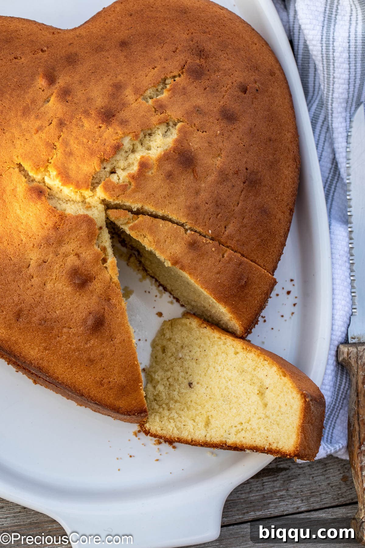A perfectly baked plain cake with several slices already taken out, revealing its soft texture.
