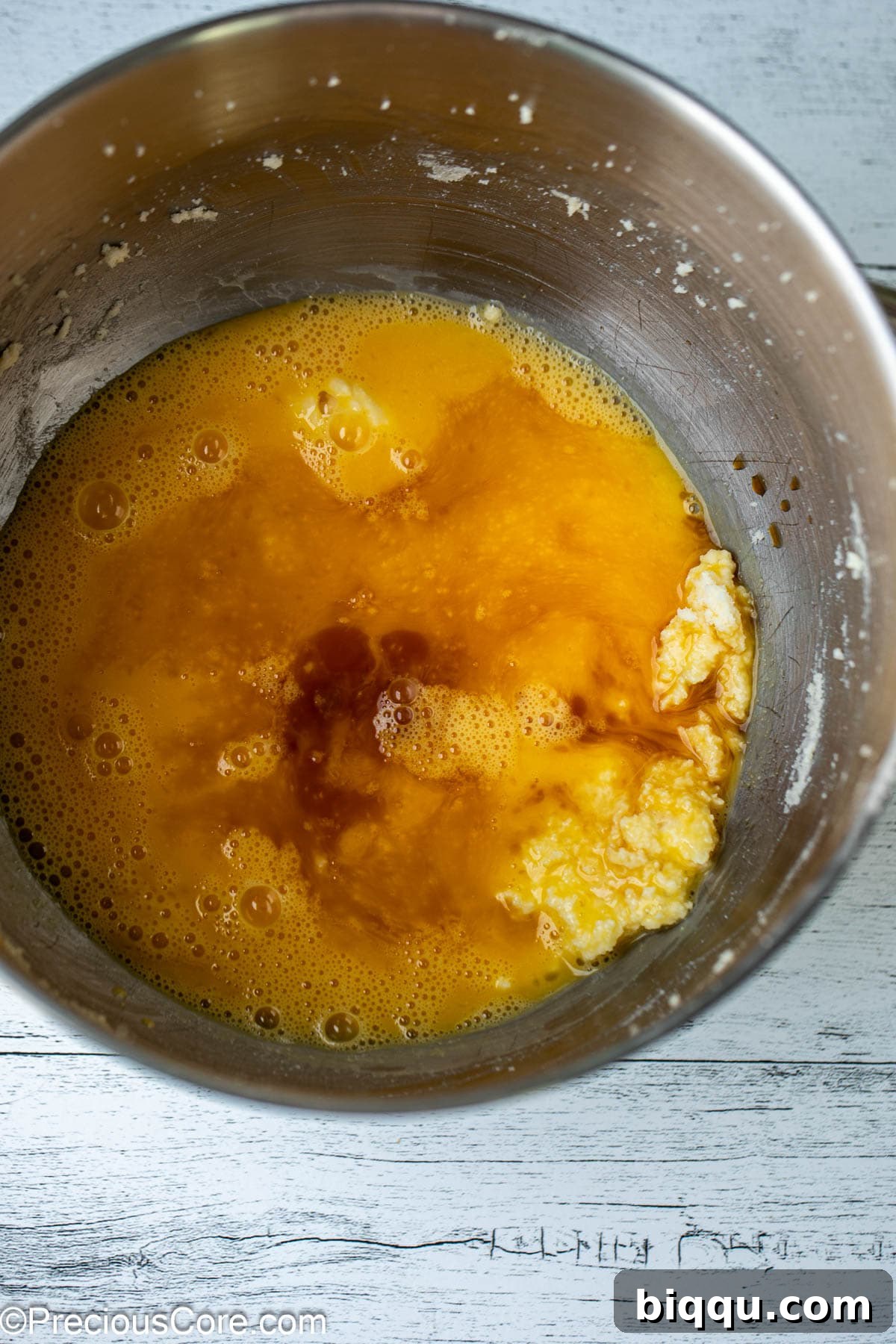 Eggs and vanilla extract being added to the creamed butter and sugar mixture.