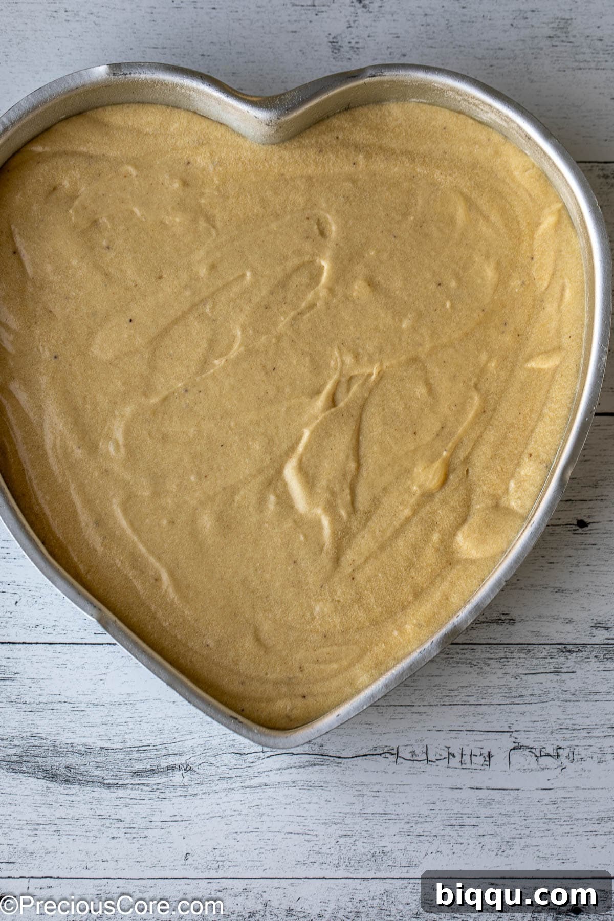 Cake batter poured into a heart-shaped baking pan, ready for the oven.