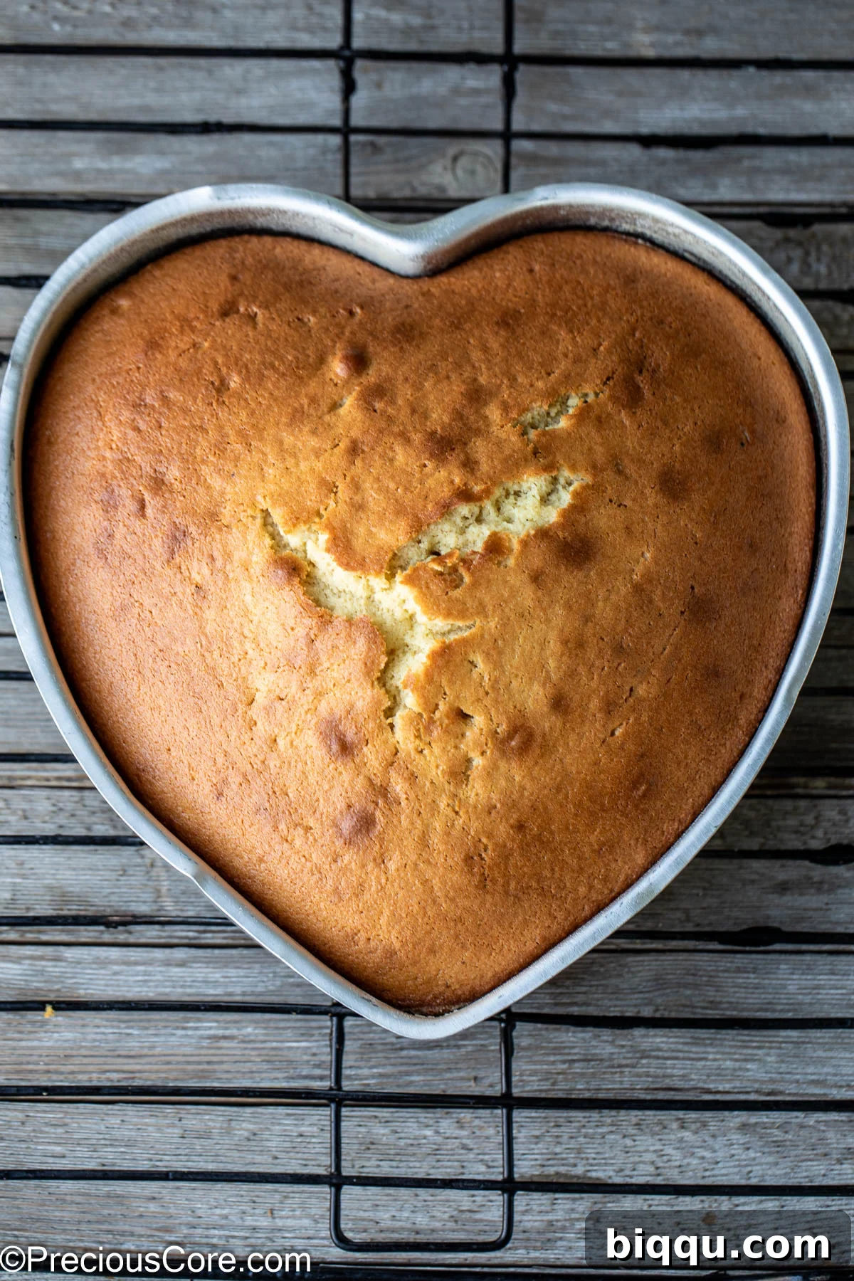 A heart-shaped plain cake cooling on a wire rack, perfectly golden.