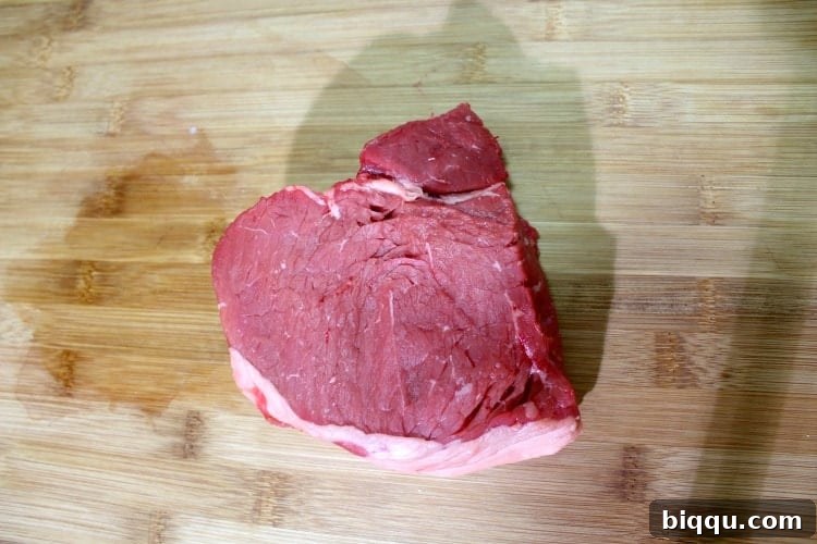 Piece of top sirloin steak on a wooden cutting board, pre-prepped for Soya.