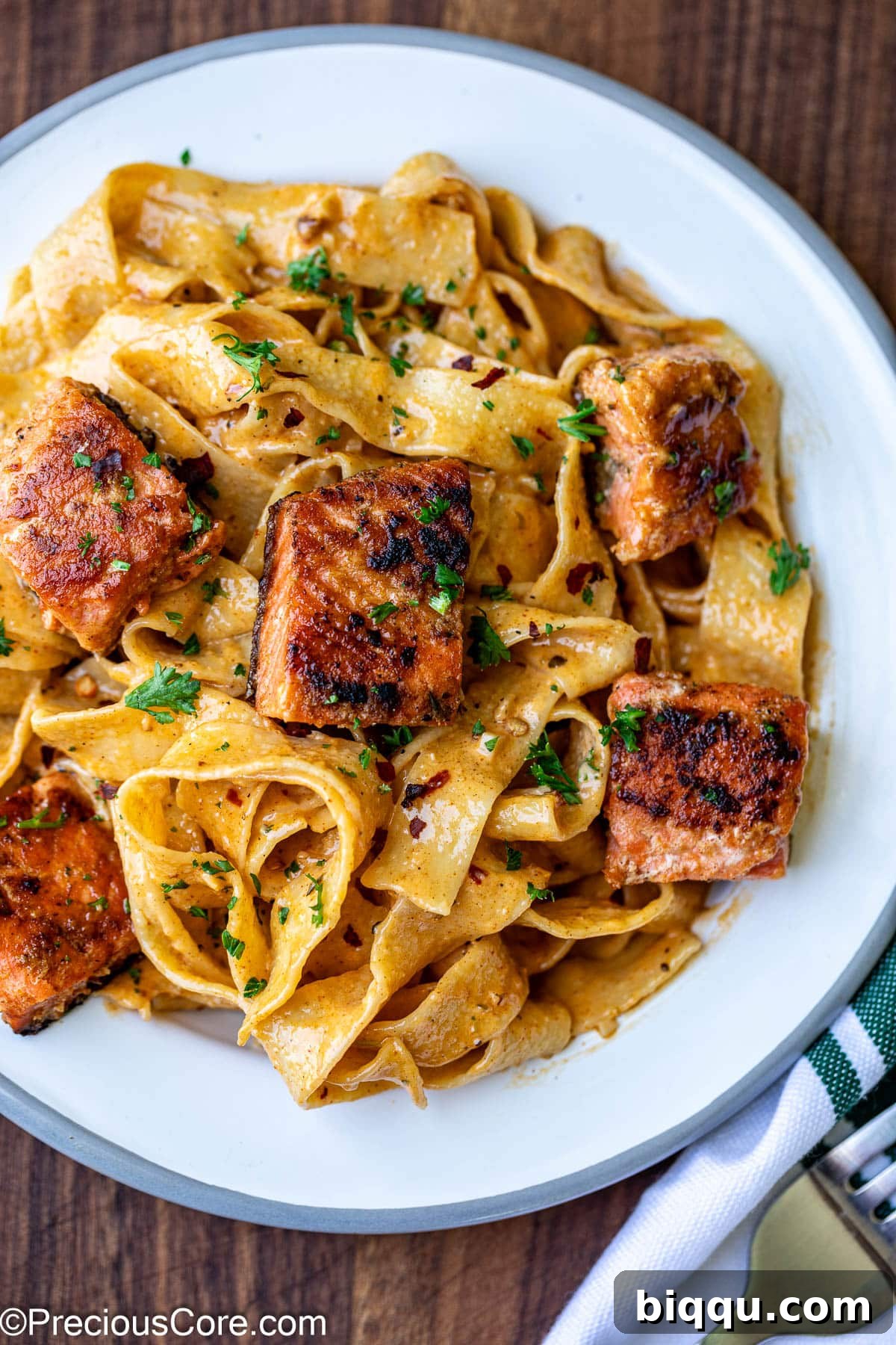 Plated Cajun Pasta With Salmon, garnished with fresh herbs.