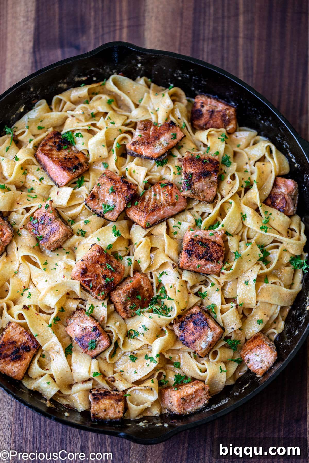Cajun pasta with seared salmon pieces mixed in, ready for serving.